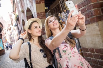 Zwei junge Frauen posieren für ein Selfie: Für Urlauber oder Studierende im Auslandssemester können Mobilfunk-Jahrespakete eine gute Lösung sein.