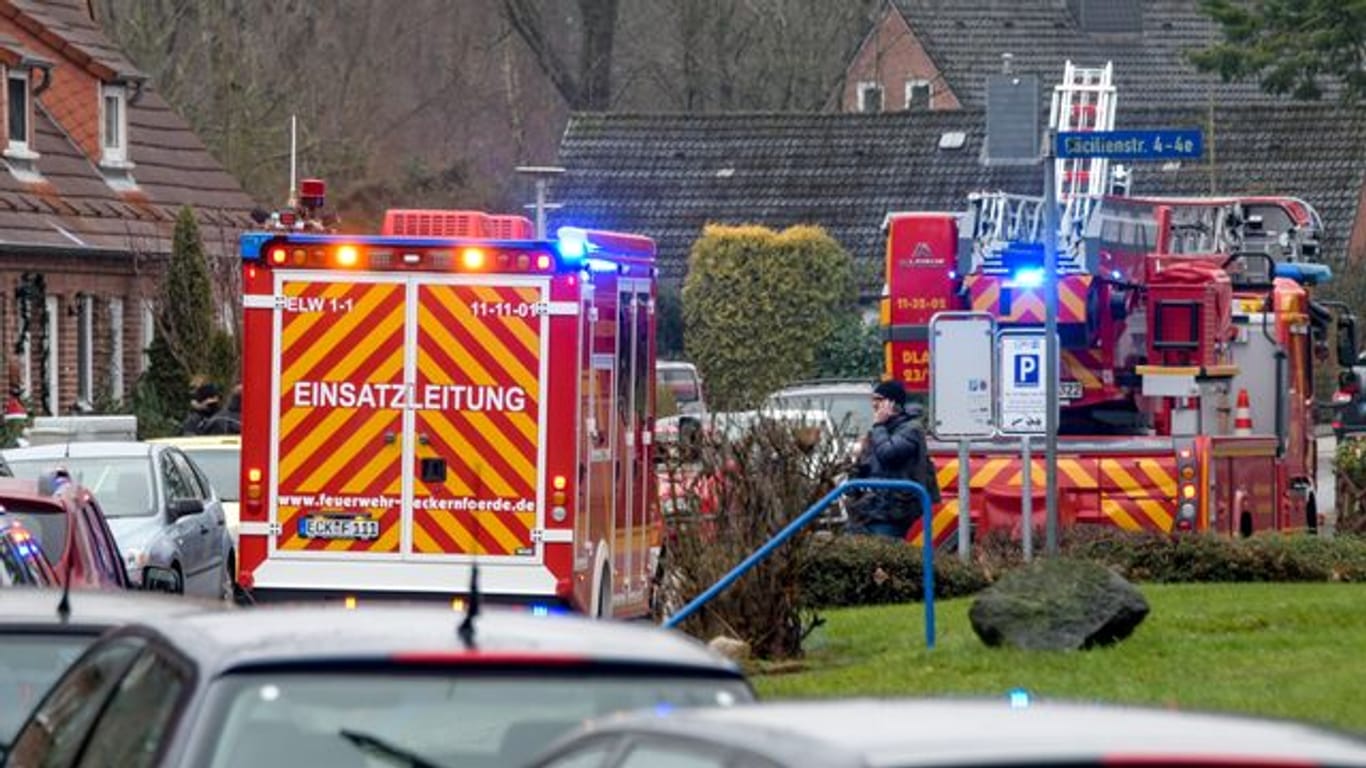 Einsatzkräfte von Polizei und Feuerwehr stehen neben einem Haus in Eckernförde, in dem sich ein junger Mann beim Herstellen von Böllern schwer verletzt hat.