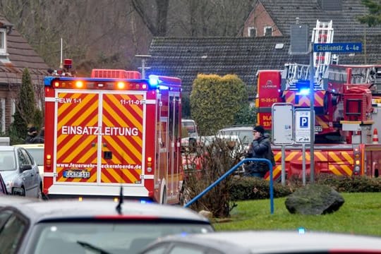 Einsatzkräfte von Polizei und Feuerwehr stehen neben einem Haus in Eckernförde, in dem sich ein junger Mann beim Herstellen von Böllern schwer verletzt hat.