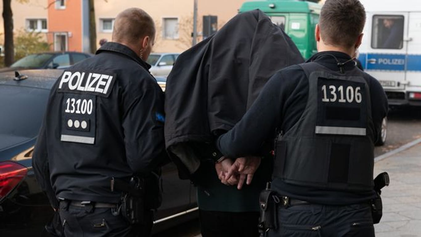 Polizeibeamte führen einen Mann nach einer Razzia in Berlin ab.