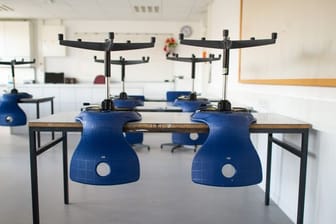 Stühle stehen in einem leeren Klassenzimmer in einem Gymnasium auf den Tischen, da der Unterricht in der Corona-Zeit ausgefallen ist.