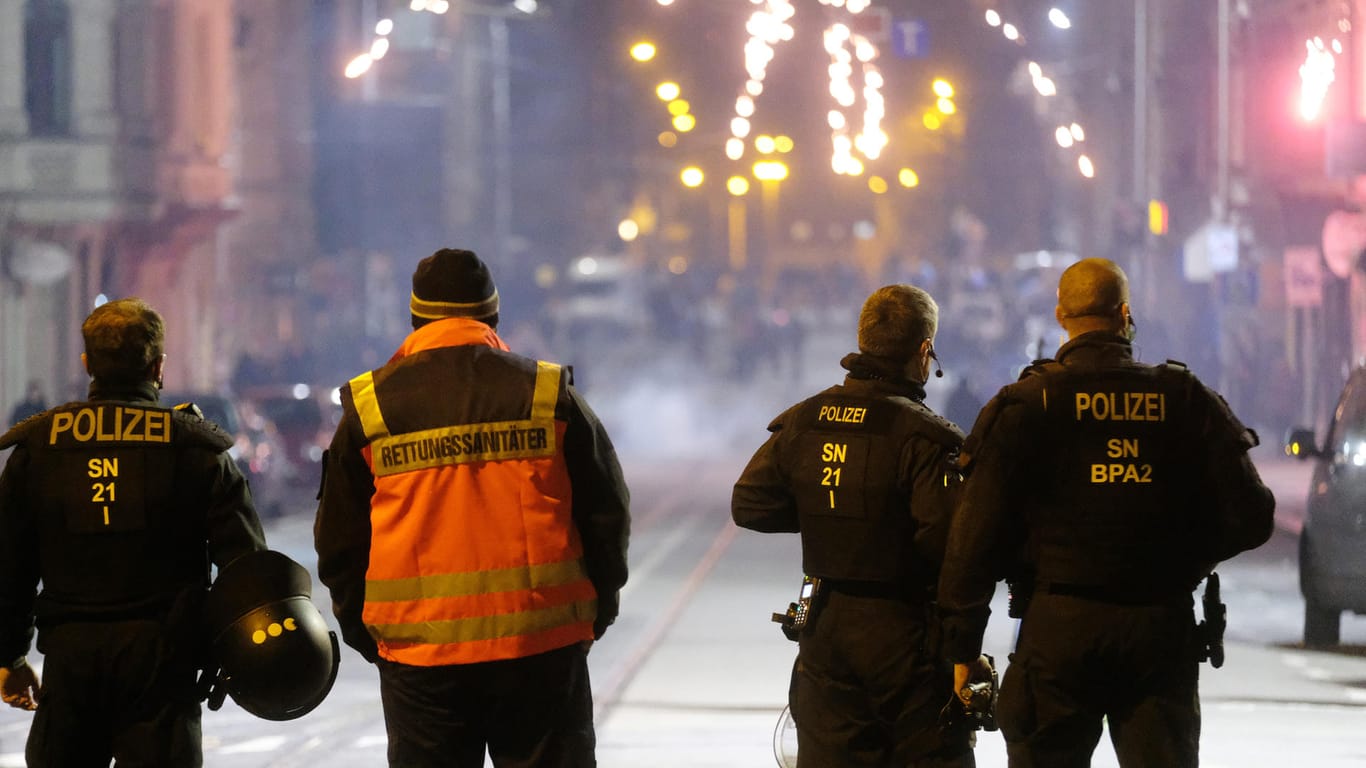 Polizisten und ein Rettungssanitäter stehen an einer Kreuzung: Die Stadt Leipzig hatte für die Silvesternacht Versammlungen verboten und in drei Zonen ein Böllerverbot erlassen.