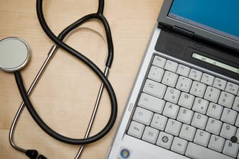 Ein Stethoskop liegt neben einem Laptop.