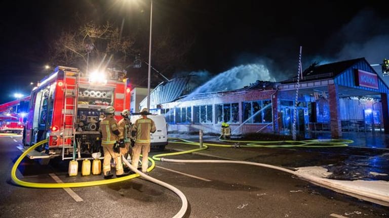 Feuerwehrleute löschen einen brennenden Supermarkt in Berlin.