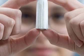 Ein Tampon wird von einer Angestellten in einer Produktionshalle gehalten.