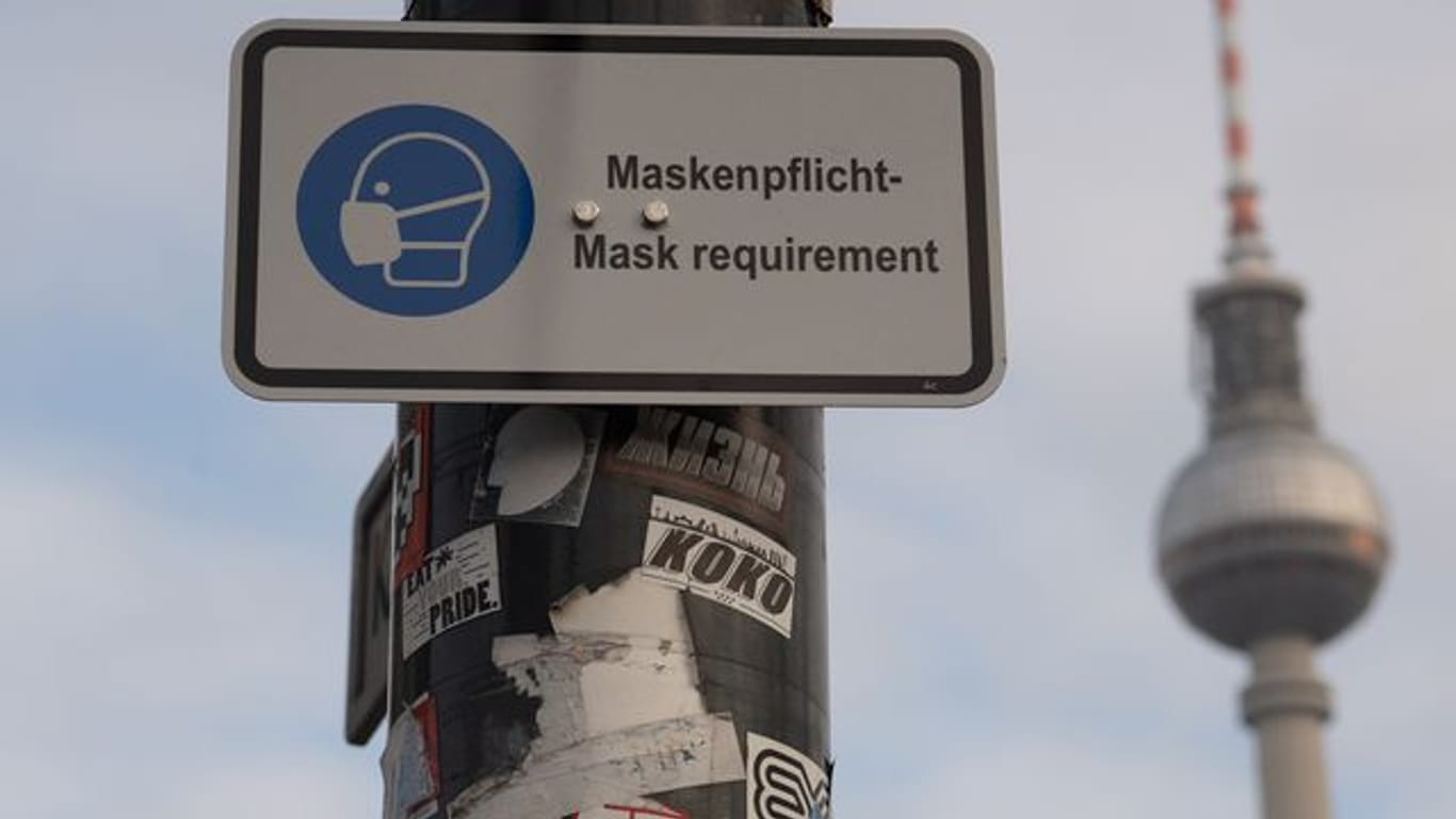 Ein Schild weist in Berlin auf die Maskenpflicht hin.