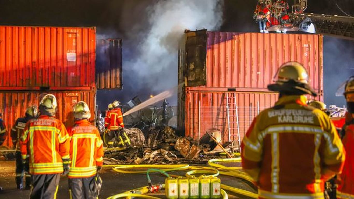 Einsatzkräfte der Feuerwehr löschen in Brand geratene Container: Bei dem Brand in Karlsruhe entstand ein hoher Sachschaden.