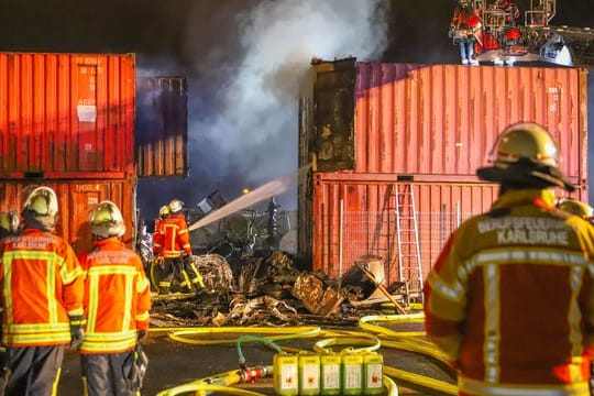 Einsatzkräfte der Feuerwehr löschen in Brand geratene Container: Bei dem Brand in Karlsruhe entstand ein hoher Sachschaden.