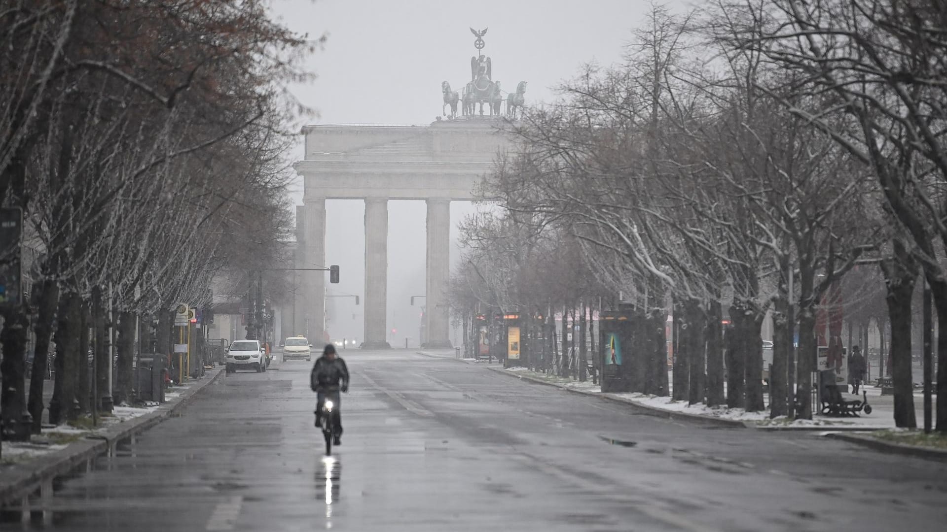 Ein Fahrradfahrer fährt durch das Schneetreiben am Brandenburger Tor: Der Schnee, der am Sonntag in dicken Flocken vom Himmel fiel, blieb teilweise liegen.