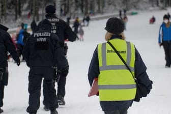 Polizisten und eine Mitarbeiterin des Ordnungsamtes stehen auf einer Piste im Skigebiet in Winterberg.