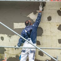 Arbeiter verputzt die Fassade eines Neubaus (Symbolbild): Im Baugewerbe nahm die Zahl der Erwerbstätigen entgegen des allgemeinen Trends zu.