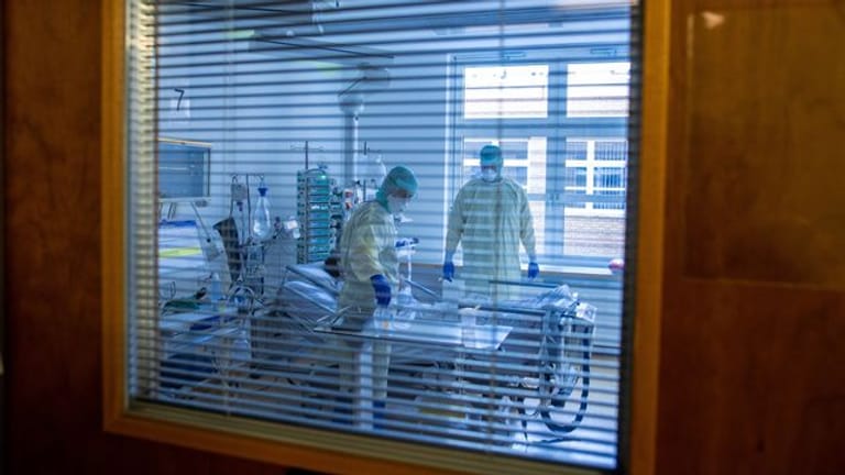 Mediziner und Pfleger versorgen einen an Covid-19 erkrankten Patienten in einem Zimmer des besonders geschützten Teils der Intensivstation des Universitätsklinikums Greifswald.