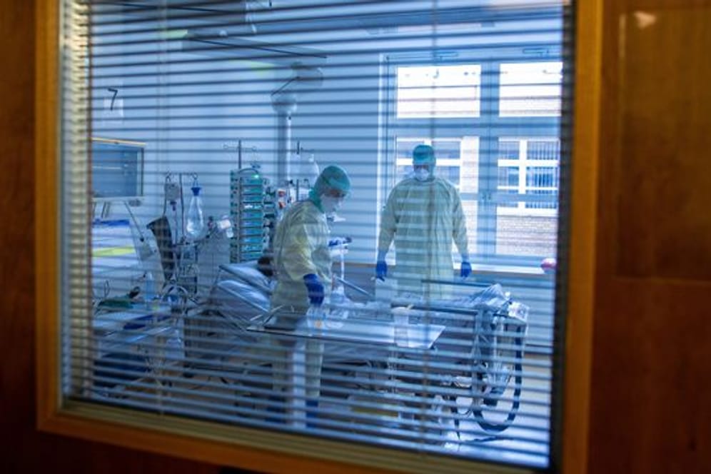 Mediziner und Pfleger versorgen einen an Covid-19 erkrankten Patienten in einem Zimmer des besonders geschützten Teils der Intensivstation des Universitätsklinikums Greifswald.