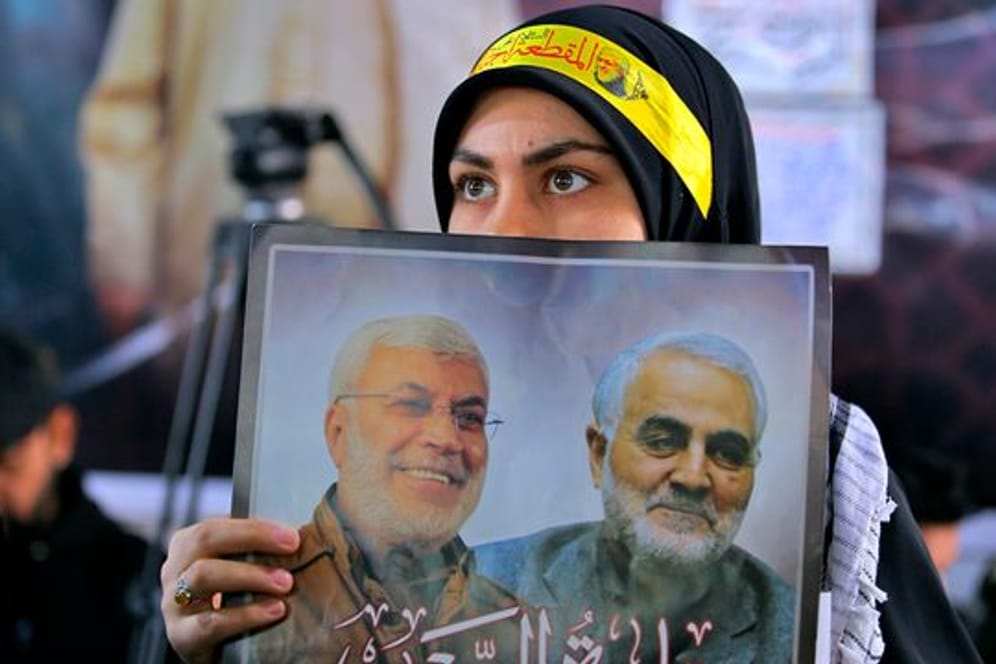 Eine Frau hält ein Bild des einflussreichen irakischen Milizen-Anführers Abu Mahdi al-Muhandis (l) und des iranischen Top-Generals Ghassem Soleimani, die am 03.
