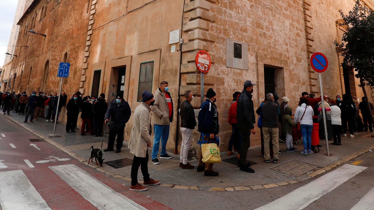 Menschen warten in einer Schlange, um ein Wohltätigkeits-Weihnachtsessen für arme und obdachlose Menschen in der Caputxins-Kirche zu bekommen.