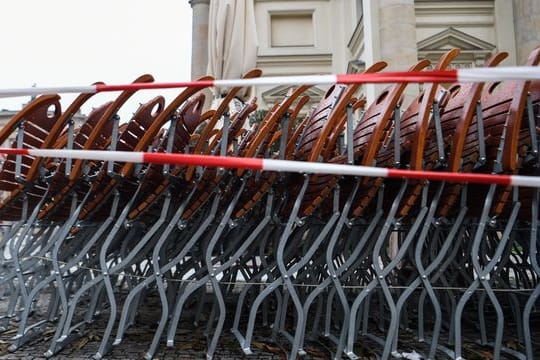 Auf dem Gendarmenmarkt in Berlin stehen zusammengestapelte Stühle hinter einem Absperrband.