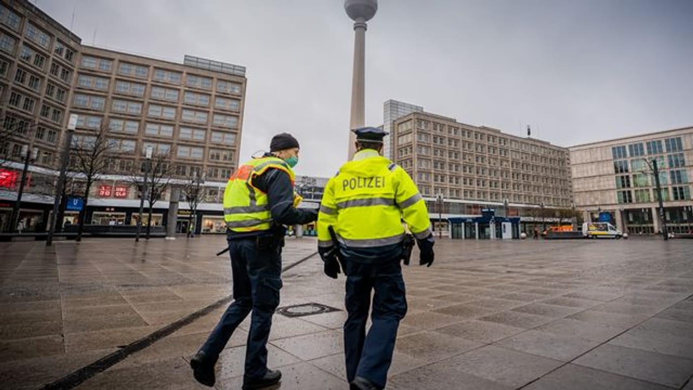 Polizisten gehen über den ansonsten weitgehend leeren Alexanderplatz in der Hauptstadt.