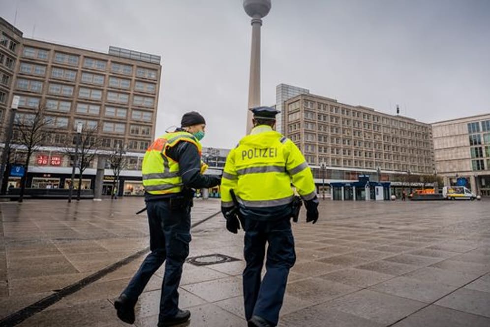 Polizisten gehen über den ansonsten weitgehend leeren Alexanderplatz in der Hauptstadt.