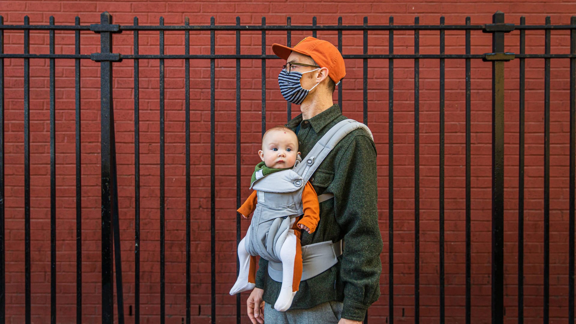 Ein junger Vater mit Mund-Nasen-Schutz trägt sein Baby in einer Trage (Symbolbild): In Essen ist 2020 auch eine kleine Corona zur Welt gekommen.