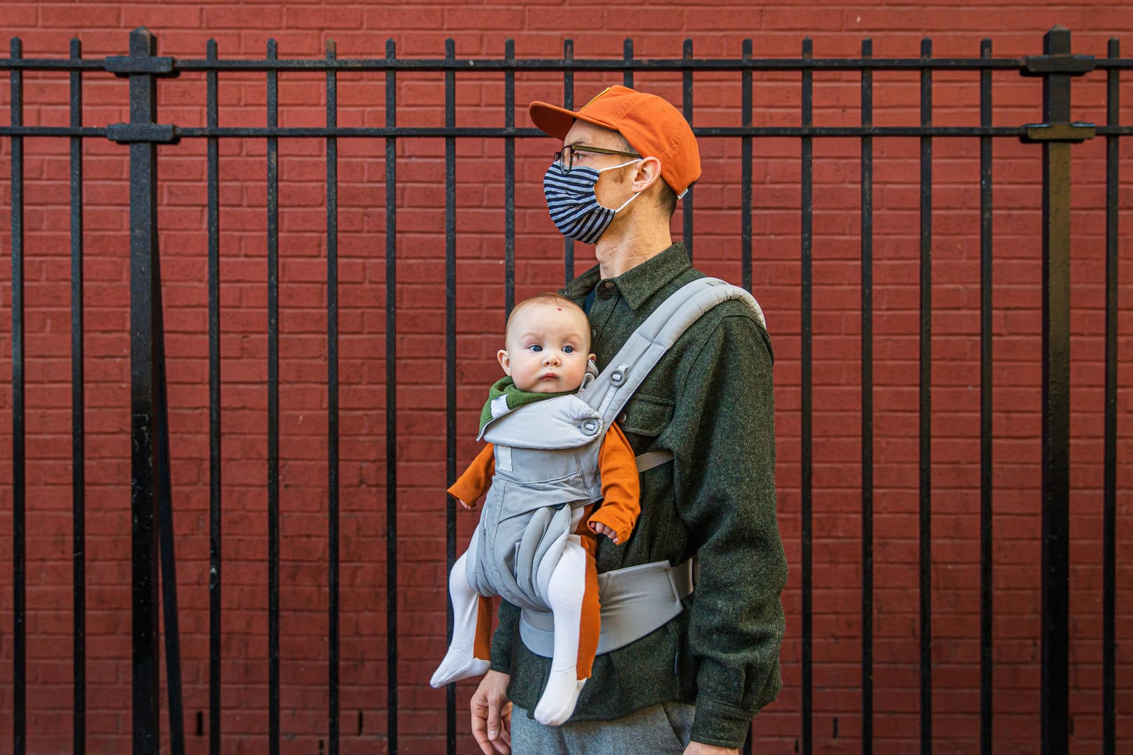 Ein junger Vater mit Mund-Nasen-Schutz trägt sein Baby in einer Trage (Symbolbild): In Essen ist 2020 auch eine kleine Corona zur Welt gekommen.