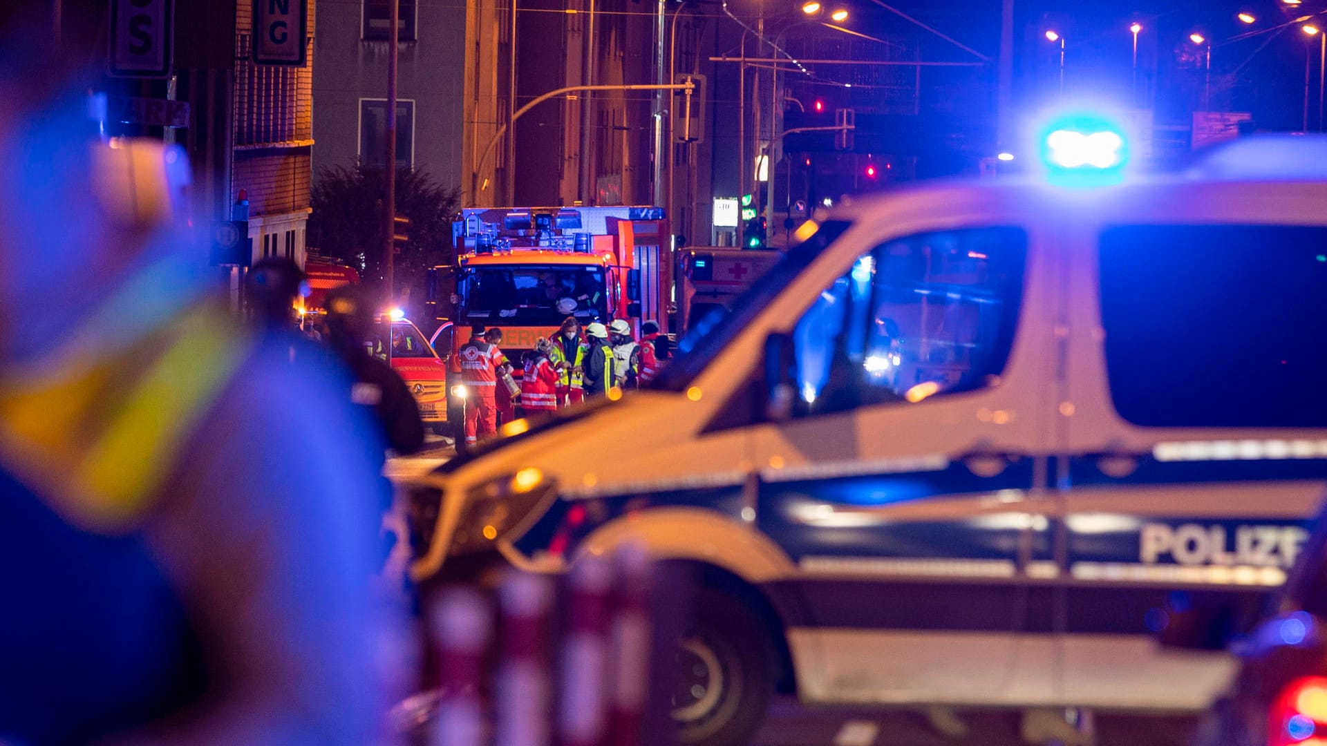 Einsatzkräfte der Polizei und Feuerwehr stehen bei ihren Fahrzeugen. Bei einem Polizeieinsatz in Mülheim ist ein mit einem Gewehr bewaffneter Mann durch einen Schuss tödlich verletzt worden.