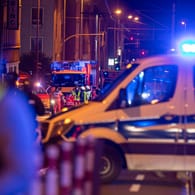 Einsatzkräfte der Polizei und Feuerwehr stehen bei ihren Fahrzeugen. Bei einem Polizeieinsatz in Mülheim ist ein mit einem Gewehr bewaffneter Mann durch einen Schuss tödlich verletzt worden.
