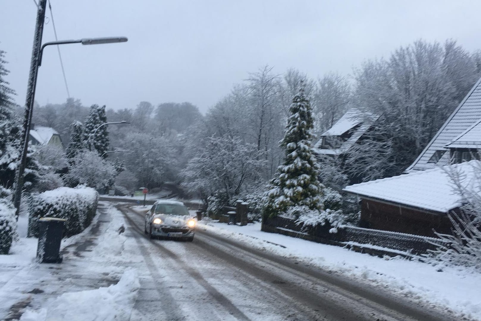 Ein Auto fährt auf dem verschneiten Westfalenweg in Wuppertal: In der Nacht hat es dort geschneit.