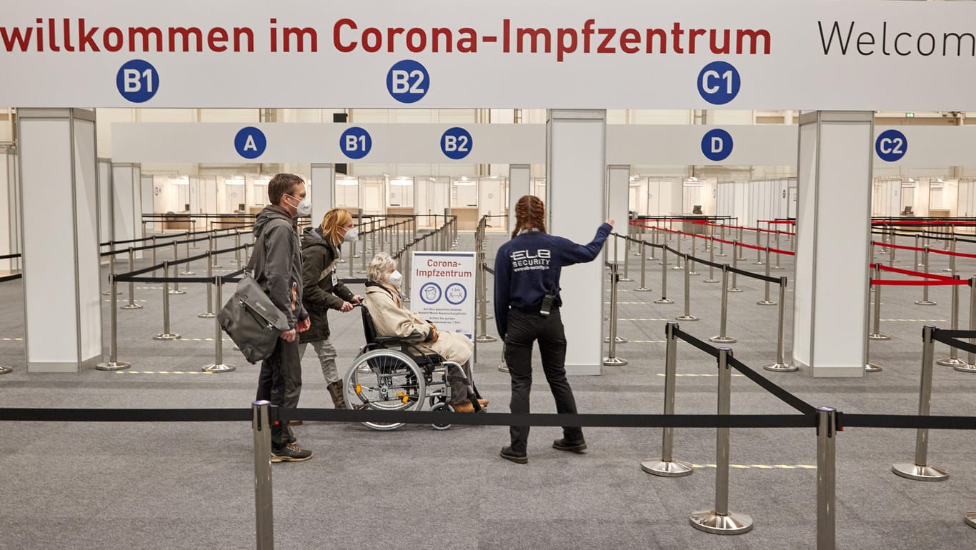 Eine Frau im Rollstuhl und Begleitpersonen lassen sich am Eingangsbereich des Corona-Impfzentrums in Hamburg: "Wir können erst richtig durchstarten, wenn mehr Impfstoff vor Ort ankommt."