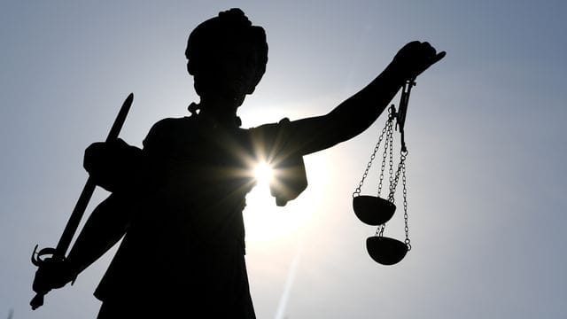 Die Statue der Justitia steht im Gegenlicht der Sonne