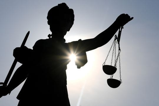 Die Statue der Justitia steht im Gegenlicht der Sonne