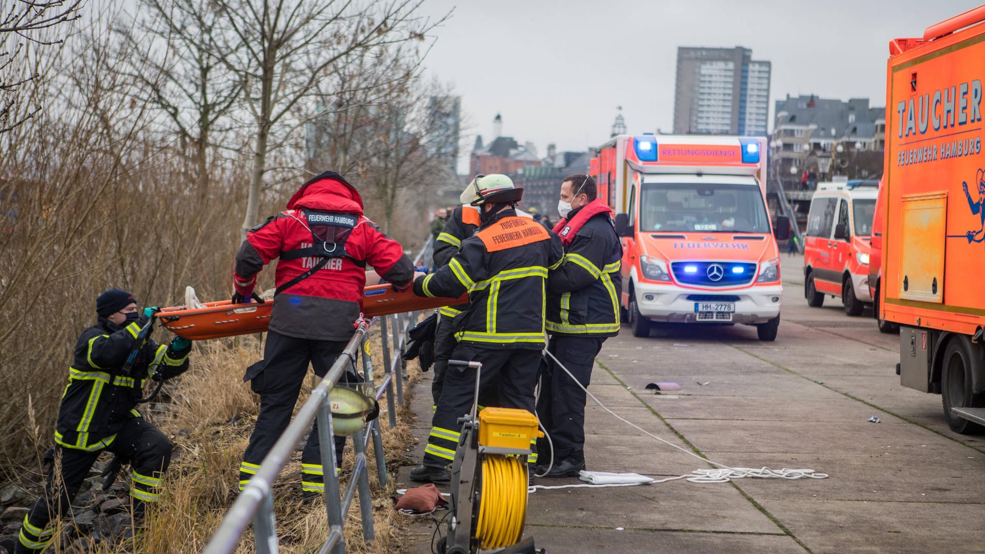 Retter heben den Verunglückten auf einer Trage über ein Geländer. Der Mann wurde in ein Krankenhaus eingeliefert.