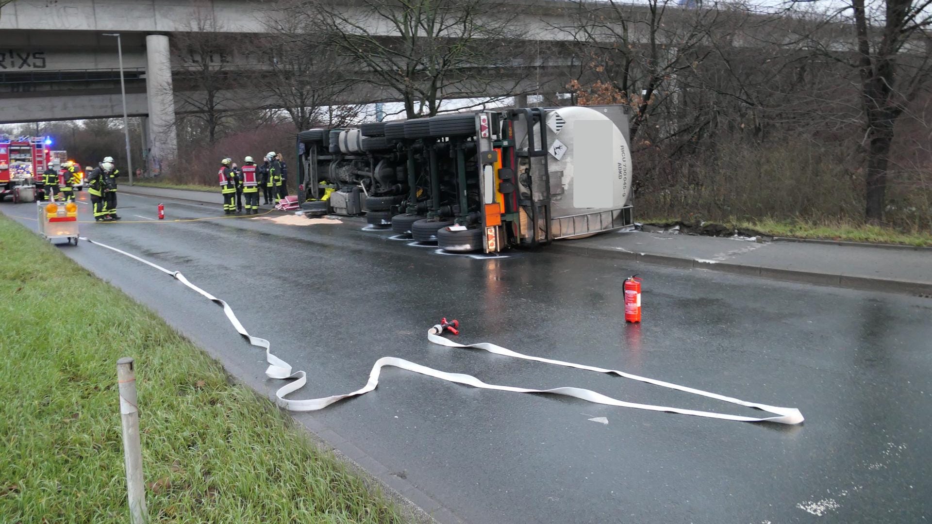 Einsatzkräfte der Feuerwehr stehen bei einem umgekippten Gefahrgut-Lastwagen: Nach einem Unfall ist eine giftige Flüssigkeit ausgelaufen. Einsatzkräfte der Feuerwehr stehen bei einem umgekippten Gefahrgut-Lastwagen: Nach einem Unfall ist eine giftige Flüssigkeit ausgelaufen.