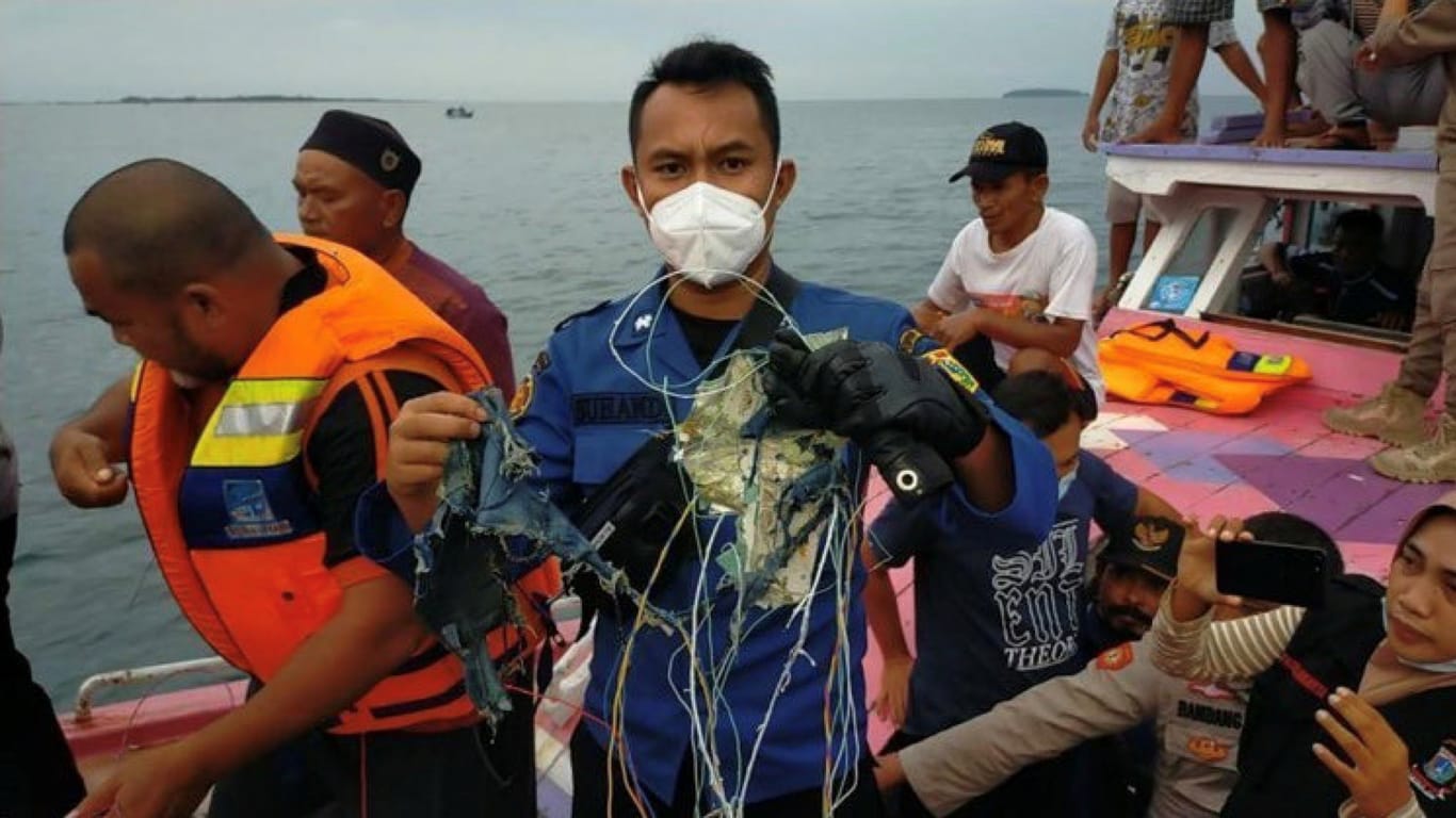 Ein Mann hält Teile hoch, die wohl zum abgestürzten Flugzeit gehörten: In Indonesien ist eine Passagiermaschine vom Radar verschwunden.