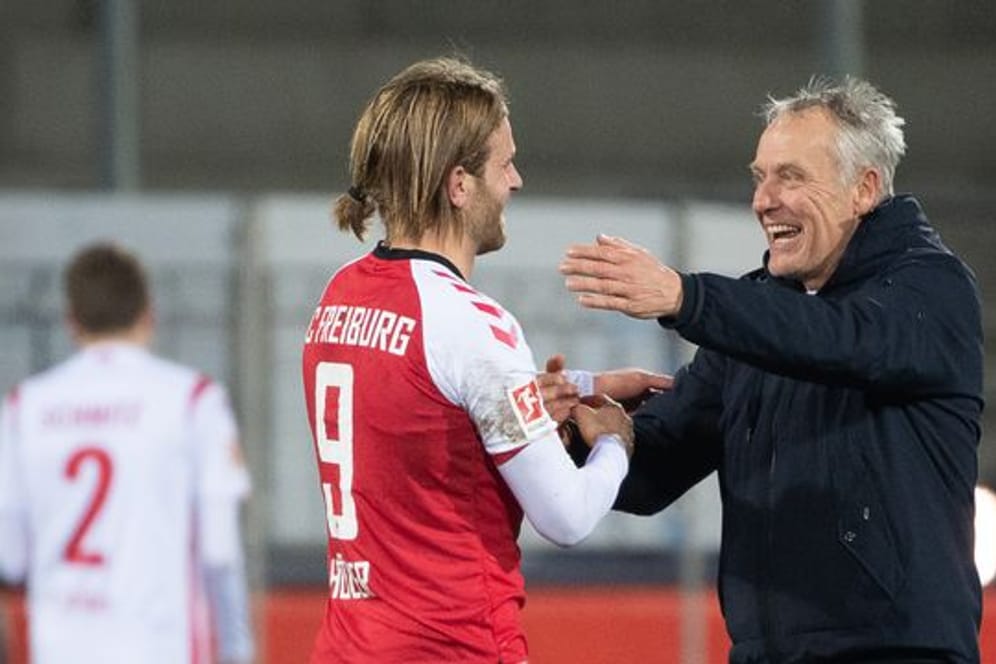 Freiburgs Trainer Christian Streich (r) freut sich nach dem Spiel mit Torschütze Lucas Höler.