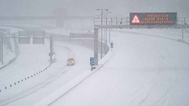 Ein Rettungsfahrzeug fährt auf der leeren, schneebedeckten Schnellstraße M-30 durch Madrid. Ein Rettungsfahrzeug fährt auf der leeren, schneebedeckten Schnellstraße M-30 durch Madrid.