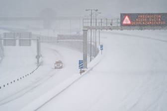 Ein Rettungsfahrzeug fährt auf der leeren, schneebedeckten Schnellstraße M-30 durch Madrid.