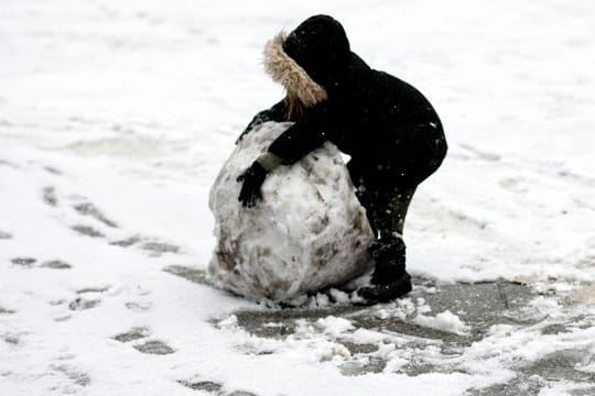 Ein Kind spielt im Schnee auf der Straße