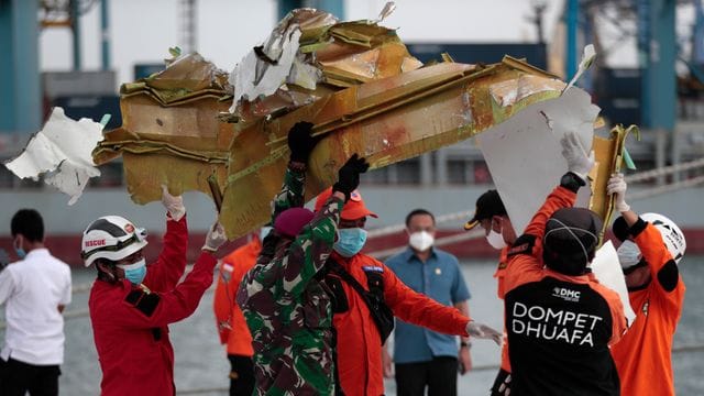 Rettungshelfer tragen ein Teil des Flugzeugs, das aus der Javasee geborgen wurde.