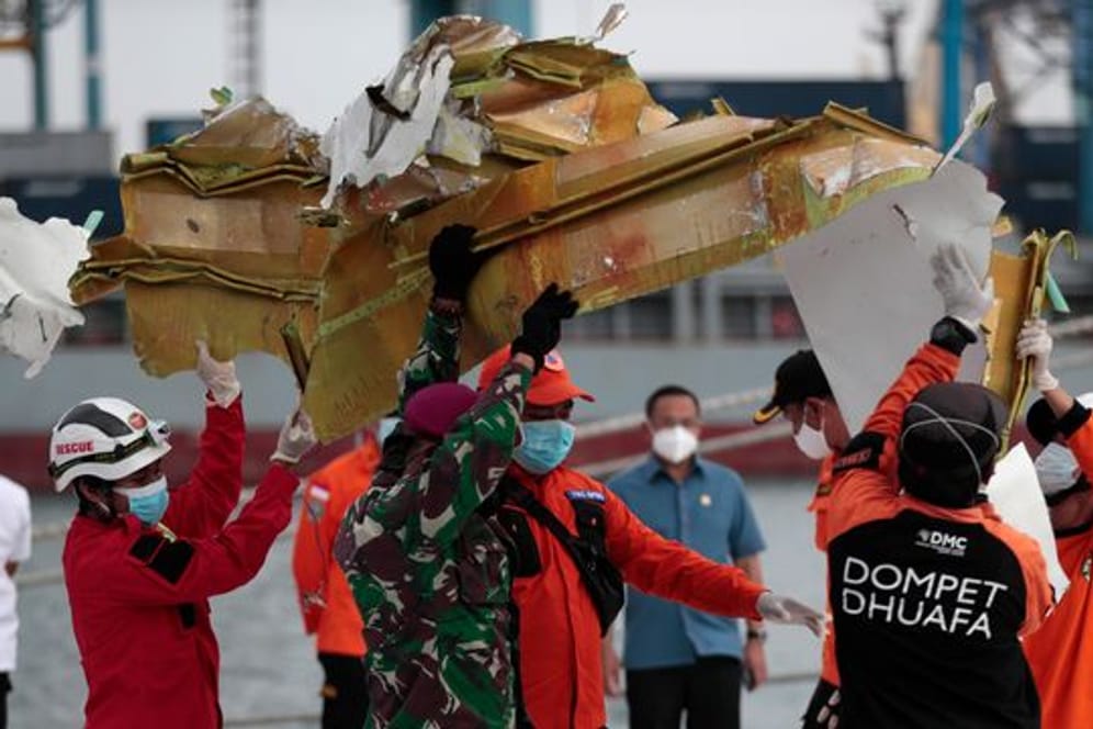 Rettungshelfer tragen ein Teil des Flugzeugs, das aus der Javasee geborgen wurde.