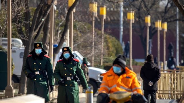 Chinesische paramilitärische Polizisten mit Mund-Nasen-Schutz patrouillieren entlang einer Straße in Peking. Chinesische paramilitärische Polizisten mit Mund-Nasen-Schutz patrouillieren entlang einer Straße in Peking.