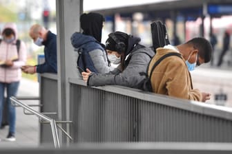 Maskenpflicht im oeffentlichen Personennahverkehr. Am Ostbahnhof warten Fahrgaeste auf ihren Zug,sie blicken auf ihre Sm