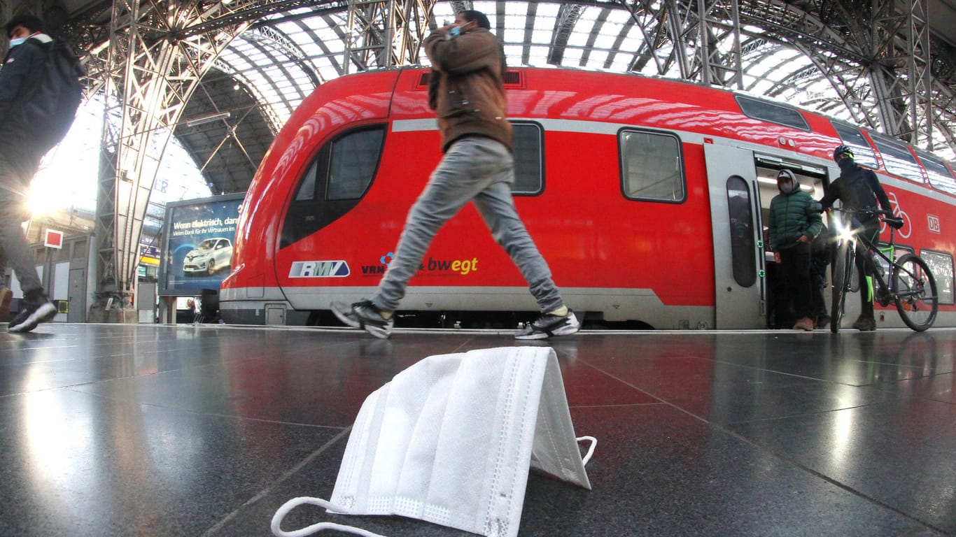 Eine Mund-Nasen-Maske liegt auf einem Bahnsteig vor einem Zug (Symbolbild): In Essen hat ein Maskenverweigerer einen Zugbegleiter bedroht.