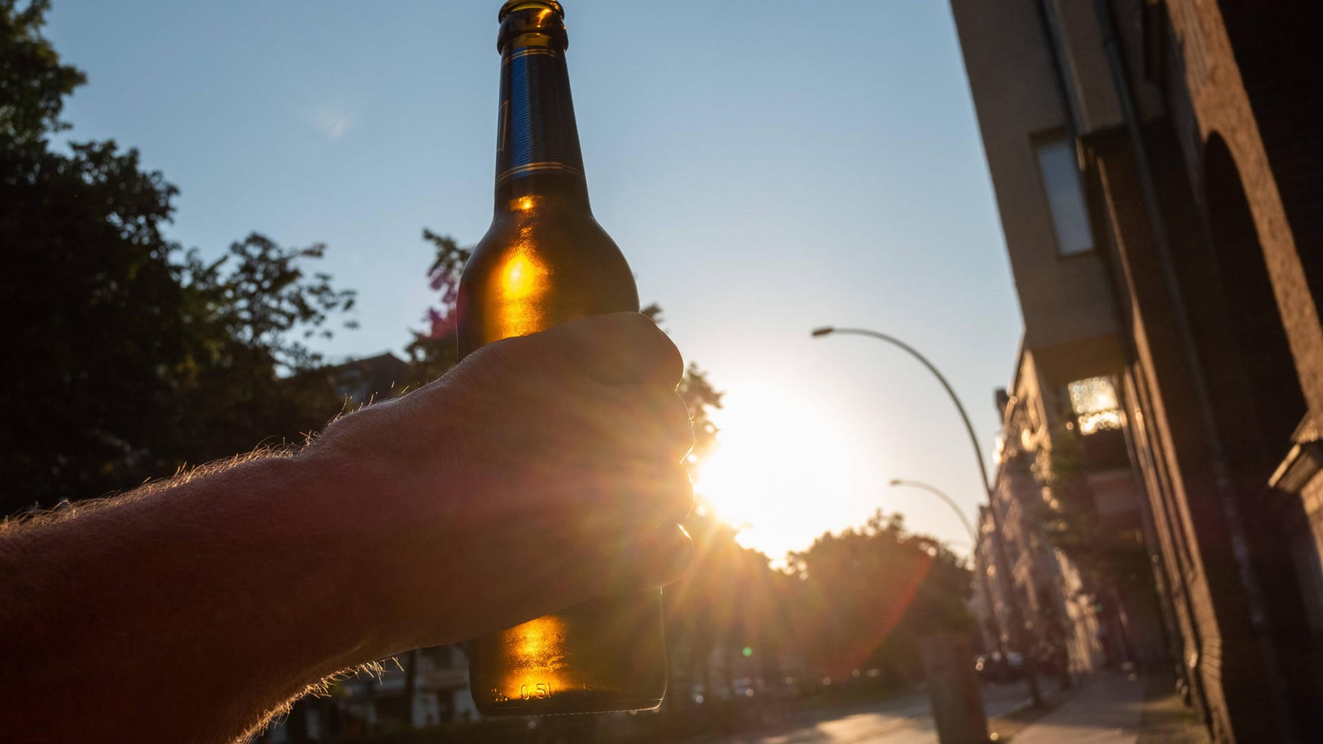 Ein Mann hält eine Bierflasche hoch (Symbolbild): Auf der B101 hat ein Lkw eine Menge Bier verloren.