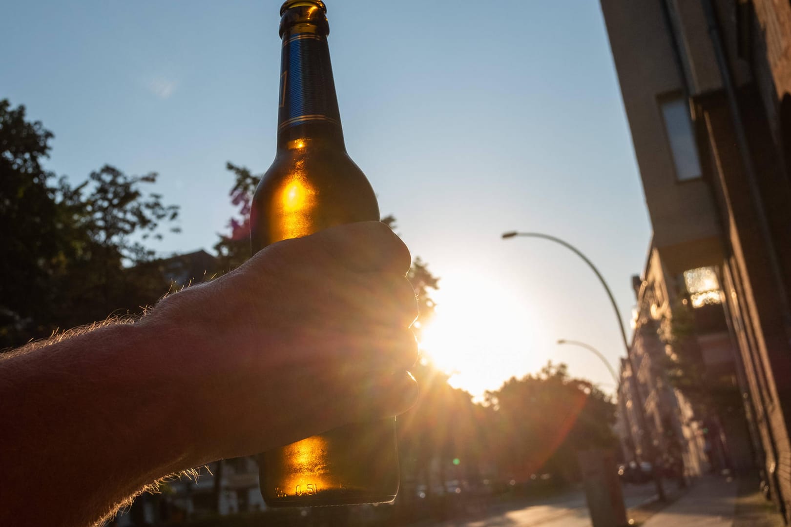 Ein Mann hält eine Bierflasche hoch (Symbolbild): Auf der B101 hat ein Lkw eine Menge Bier verloren.