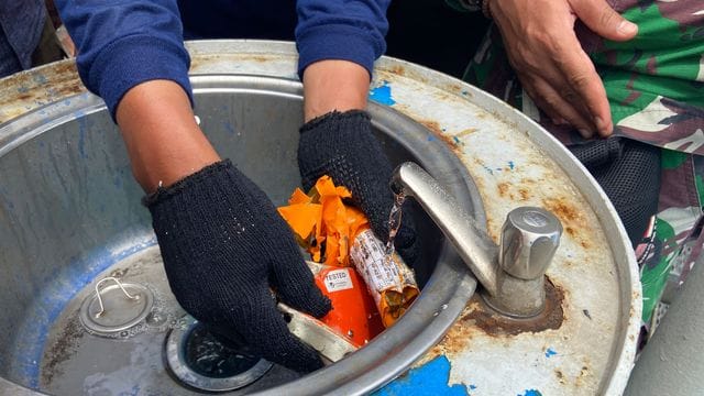 Ein Mitglied der indonesischen Marine inspiziert ein Teil des Flugdatenschreibers. Ein Mitglied der indonesischen Marine inspiziert ein Teil des Flugdatenschreibers.
