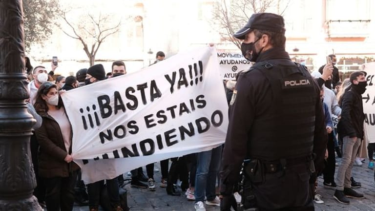 "Schluss damit, ihr ruiniert uns" steht auf einem Banner, das Demonstranten während einer Kundgebung gegen die Corona-Maßnahmen in Palma de Mallorca halten.
