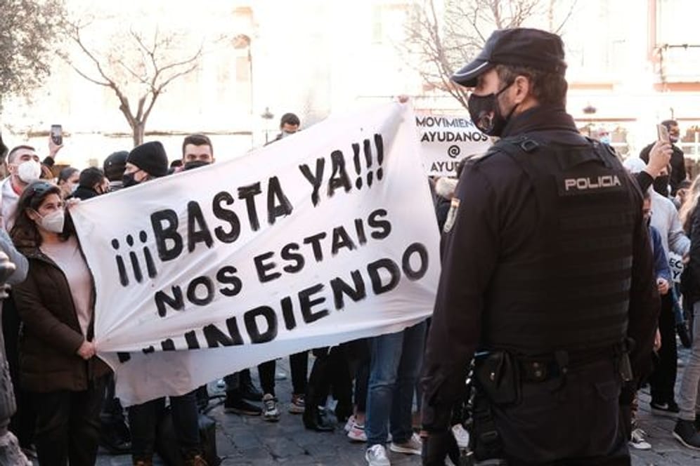 "Schluss damit, ihr ruiniert uns" steht auf einem Banner, das Demonstranten während einer Kundgebung gegen die Corona-Maßnahmen in Palma de Mallorca halten.