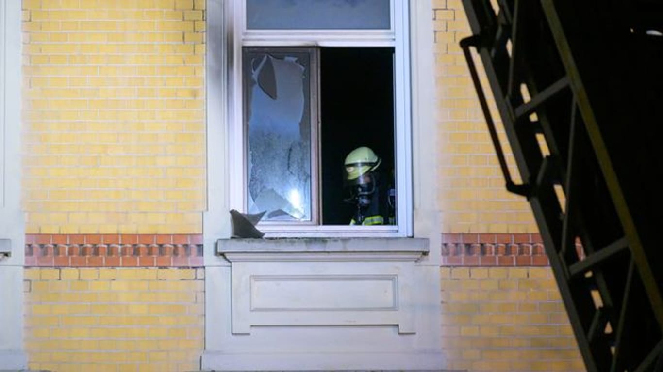 Ein Feuerwehrmann steht im Fenster der Brandwohnung in Altona: Eine Frau kam bei dem Feuer ums Leben.