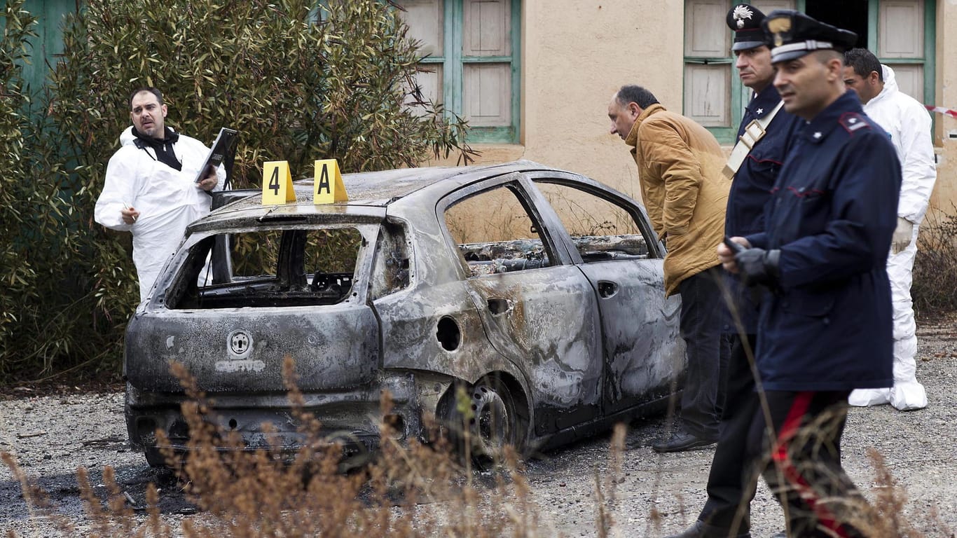 Ermittler arbeiten an einem verbrannten Auto, in dem drei verbrannte Leichen in Süditalien, gefunden wurden. Berichten zufolge wurde ein dreijähriger Junge angeblich von rivalisierenden 'Ndrangheta-Mafia-Banden getötet.
