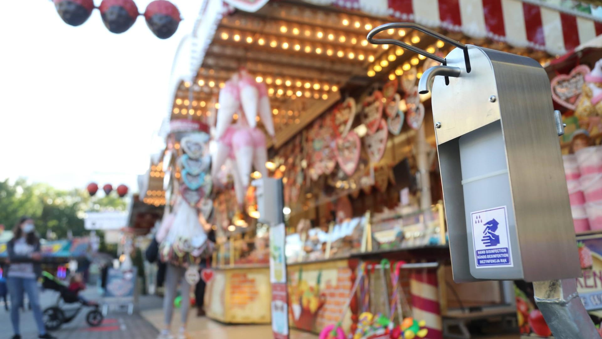 Ein Spender für Desinfektionsmittel steht vor einem Süßwarenstand (Symbolbild): Bundestagsabgeordneter Stefan Pilsinger fordert eine Wiesn 2021 für Geimpfte. Ein Spender für Desinfektionsmittel steht vor einem Süßwarenstand (Symbolbild): Bundestagsabgeordneter Stefan Pilsinger fordert eine Wiesn 2021 für Geimpfte.